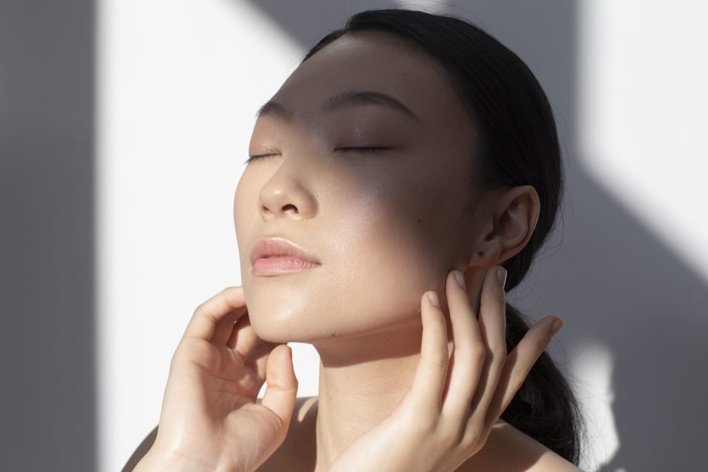 Femme coréenne affichant une peau sans défaut grâce à la k-beauty. 