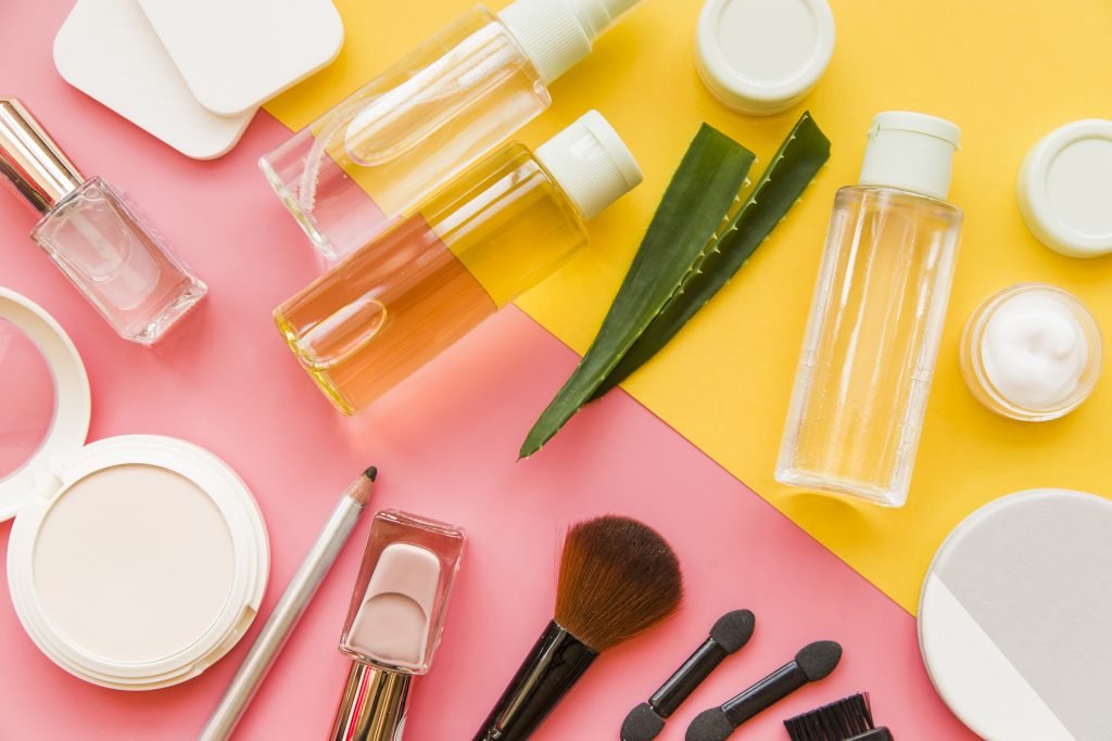 Des cosmétiques de k-beauty et du maquillage exposés sur un fond rose et jaune.